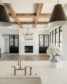 a large kitchen with white counter tops and black pendant lights hanging from the ceiling above it