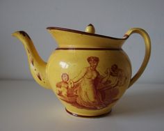 a yellow teapot with an image of a woman and children painted on the side