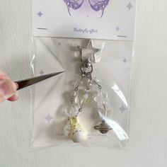 a pair of scissors is being used to cut the keychain for a doll