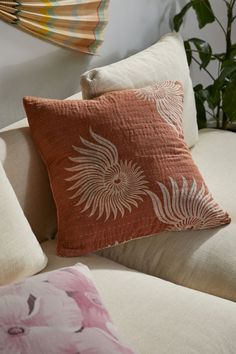 the pillows on the couch are decorated with flowers and leaves in shades of orange, pink, yellow and white