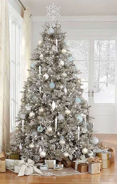 a white christmas tree with silver ornaments and snowflakes