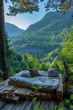 a bed made out of wood on top of a wooden platform in the woods with mountains in the background