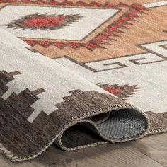 an area rug is laying on the floor with it's end rolled up to show its design