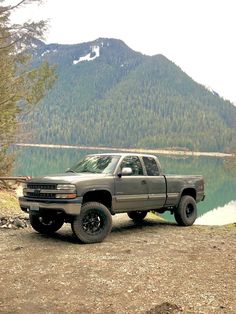 a gray truck parked on the side of a lake