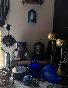 there are many different items on the table in front of the window, including vases and candles