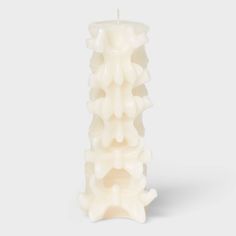 a white candle that is sitting in the shape of a flower on a gray background