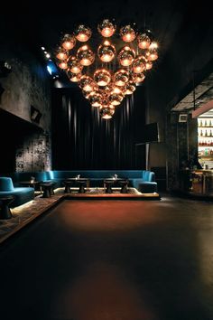 a dimly lit room with blue couches and lights hanging from the ceiling above it