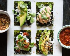 four square pieces of sushi with avocado, tomatoes and other toppings