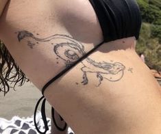 a man with a tattoo on his back is sitting at the beach and looking into the water