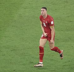 a male soccer player in a red uniform is on the field and ready to kick the ball