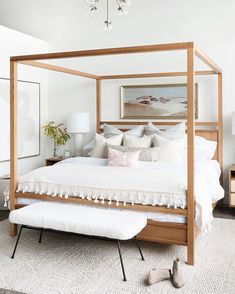 a bed with white sheets and pillows in a room that has a chandelier hanging from the ceiling