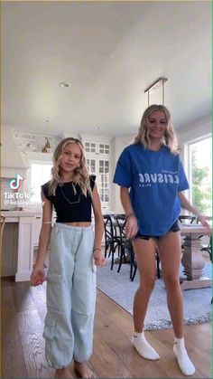 two girls standing in the middle of a living room