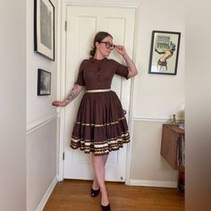 This is a gorgeous 1950s Vintage handmade patio / rodeo / line dancing set.  Two pieces, it is made of a brown cotton material. The top has 3/4 length sleeves and buttons down the front with a slight collar at the neck. The sleeves are frilly / fluttered at the end with gold Rickrack zig-jagged trim.  The skirt is full and tiered and banded at the waist with a gold ribbon. The same metallic Rickrack trim is along the edges of each of the tiers.  Set is modeled wearing a crinoline. The skirt hook Western Patio, Vintage Patio, Womens Suits, Western Vintage, Line Dance, 50s Vintage, Line Dancing, Gold Ribbon, Vintage Western