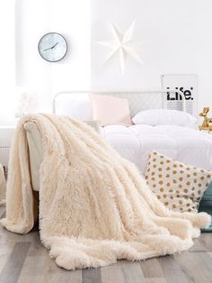 a white bed sitting next to a wooden floor in a bedroom under a large blanket