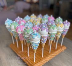 there are many colorful desserts on the sticks in this display case and they look like they have been dipped with icing or sprinkles