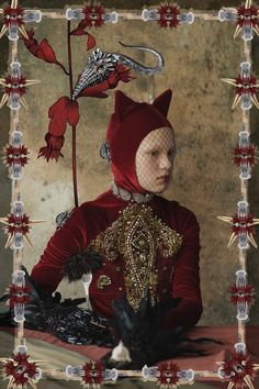 a woman dressed in red and gold sitting on a table next to a black cat