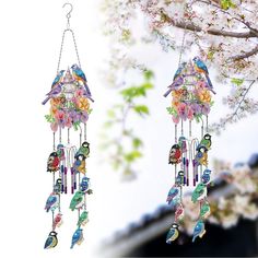 two birds are hanging from the branches of a tree with flowers and birdcages