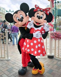 a woman standing next to mickey and minnie mouse