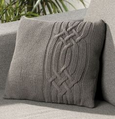 a close up of a cushion on a couch with a plant in the back ground