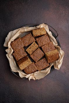 brownies cut into squares on top of parchment paper in a black plate with a cloth