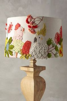 a lamp that is on top of a wooden base with flowers and birds painted on it