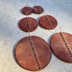 Distressed chestnut brown leather disks, with hand-sewn pyrite beads, hang from surgical steel ear wires. Three sizes and so light, you'll forget you're wearing them. Small; 1.75" L x 1.25" W Medium: 2.5L x 1.75W Large: 3"L x 2.25"W Leather And Metal Earrings, Simple Leather Earrings, Handmade Leather Earrings Ideas, Handmade Rust Leather Jewelry, Stamped Leather Earrings, Handmade Circular Brown Jewelry, Handmade Brown Circular Jewelry, Brown Leather Jewelry With Soldered Details, Unique Hand Forged Brown Earrings