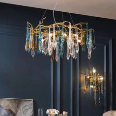 a chandelier hanging over a dining room table with plates and glasses on it