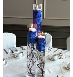 two tall vases filled with blue flowers and candles