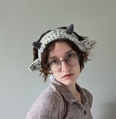 a woman wearing glasses and a knitted hat with horns on it's head