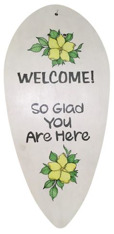 a white sign with yellow flowers on it that says, welcome so glad you are here