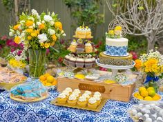 a table topped with cakes and cupcakes next to lemons in vases