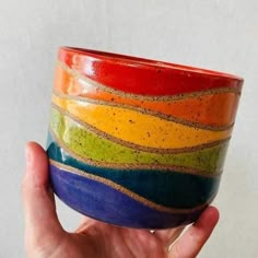 a hand holding a multicolored ceramic bowl