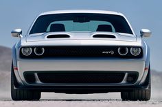 the front end of a silver car on a desert road