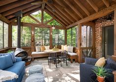 a living room filled with lots of furniture under a wooden roof covered in glass walls