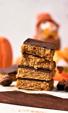 three bars stacked on top of each other with nuts and chocolate in the foreground