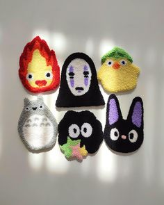 six knitted animal faces are displayed on a white surface with light shining in the background