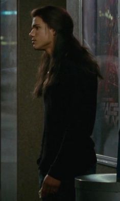 a woman standing in front of a window next to a man with long dark hair