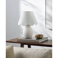 a white lamp sitting on top of a wooden table next to a book and bowl