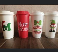 four cups with christmas designs on them sitting next to each other in front of a wall