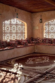 the sun shines through two large windows in an ornately decorated room with decorative rugs