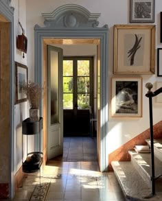 an entry way with pictures on the wall and stairs leading up to it's door