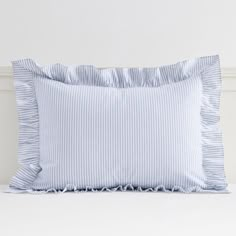 a blue and white striped pillow sitting on top of a bed next to a wall