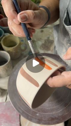 a person painting on a plate with a brush