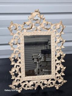 an ornate white mirror sitting on top of a black table next to a garage door