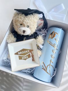 a teddy bear in a graduation cap and gown next to a blue bottle