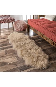 a long sheepskin rug is on the floor next to a red bench and chair