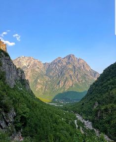 the mountains are covered in green vegetation and trees, with a river running between them