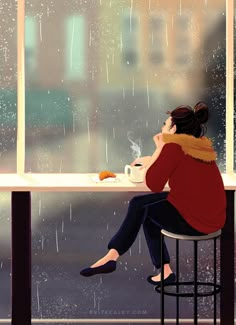 a woman sitting at a table in front of a window drinking coffee and looking out the rain