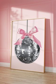 a mirror frame with a disco ball hanging from it's side in front of a pink wall