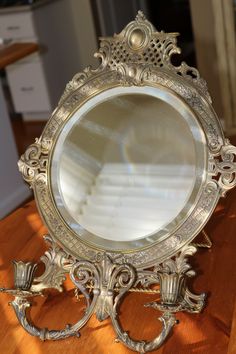 an ornate silver mirror sitting on top of a wooden table